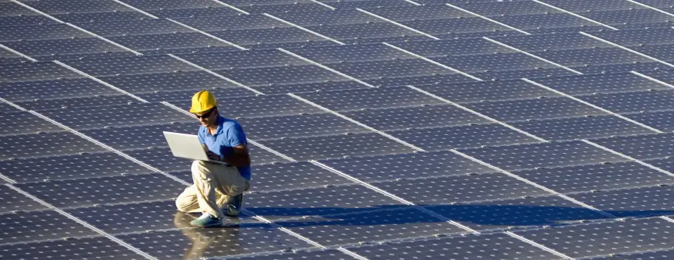 Technician on computer analyzes solar panels